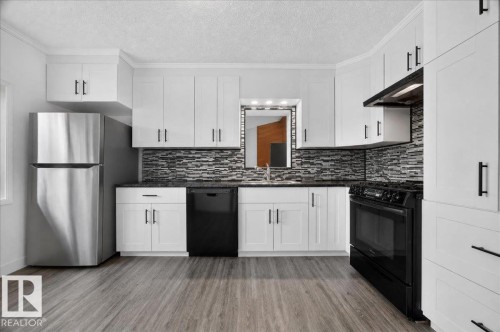 White shaker cabinetry with black hardware, wood-finish flooring, stainless steel refrigerator, black range, and stone backsplash - 543069 Range Road 191, Rural Lamont County, AB - Indoor Photo Showing Kitchen With Upgraded Kitchen
