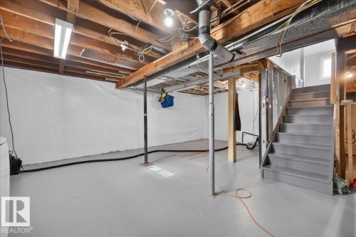 Expansive unfinished basement with exposed wood joists and structural beams, painted gray concrete floor, and painted gray staircase - 543069 Range Road 191, Rural Lamont County, AB - Indoor Photo Showing Basement