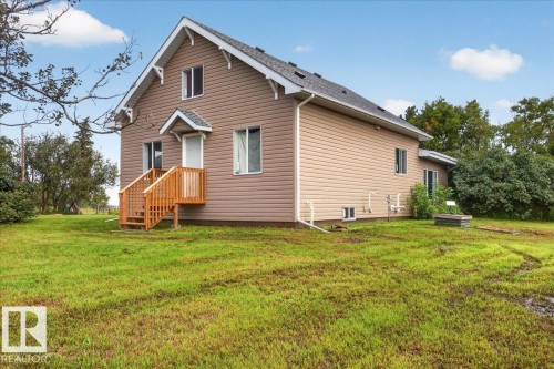 Two-story dwelling featuring brown siding, white trim, a dark shingle roof, and a wood deck with stairs leading to the entrance - 543069 Range Road 191, Rural Lamont County, AB - Outdoor