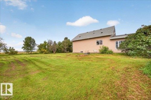 Expansive grassy yard with mature trees and a residential structure featuring light-colored siding and a dark shingle roof - 543069 Range Road 191, Rural Lamont County, AB - Outdoor