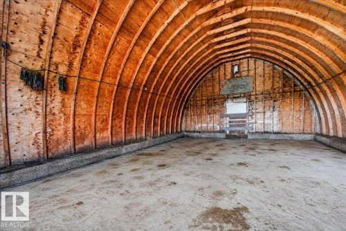 Arched wood-panel ceiling with exposed wood beams, concrete flooring, and unfinished wall paneling - 543069 Range Road 191, Rural Lamont County, AB - Indoor