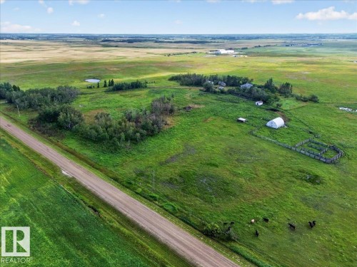 Expansive green acreage with a visible dirt road, multiple outbuildings, and a natural pond - 543069 Range Road 191, Rural Lamont County, AB - Outdoor With View