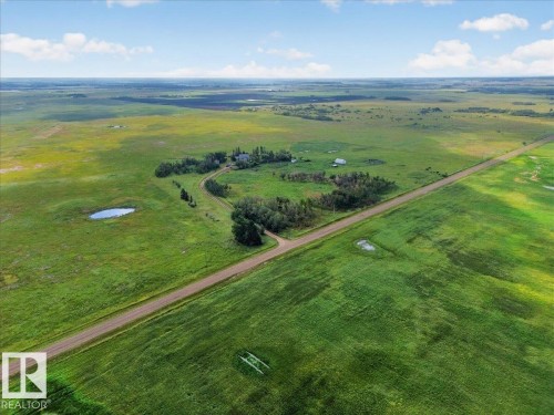 Expansive property featuring a residence, detached buildings, a winding driveway, and natural water features surrounded by open green fields - 543069 Range Road 191, Rural Lamont County, AB - Outdoor With View