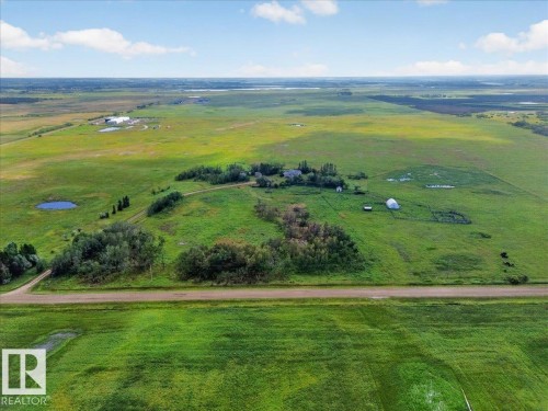 Expansive green acreage with diverse topography, featuring a cluster of buildings, a dirt road, and multiple natural water features - 543069 Range Road 191, Rural Lamont County, AB - Outdoor With View