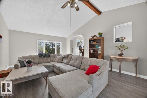 Vaulted ceiling with exposed wood beam, ceiling fan, large picture window, wood-finish flooring, and arched entryway - 543069 Range Road 191, Rural Lamont County, AB - Indoor Photo Showing Living Room