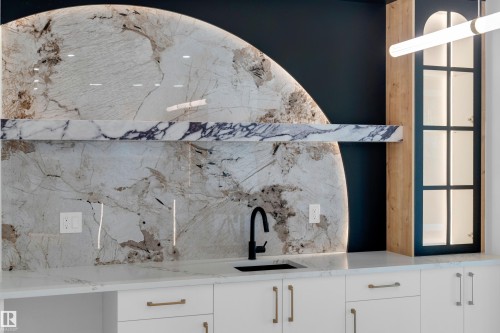 White cabinetry with gold-tone hardware, white countertop, black sink, and black faucet - 2408 1 Avenue Sw, Edmonton, AB - 