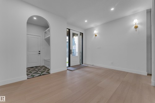 Bright, open living space featuring warm wood-finish flooring throughout, recessed ceiling lighting, and brass wall sconces - 2408 1 Avenue Sw, Edmonton, AB - Indoor Photo Showing Other Room
