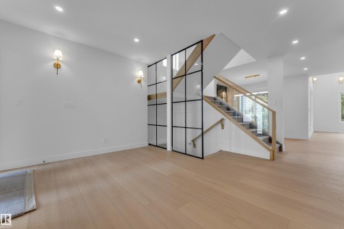 Light wood-finish flooring, recessed lighting, and modern gold-finish wall sconces - 2408 1 Avenue Sw, Edmonton, AB - Indoor Photo Showing Other Room