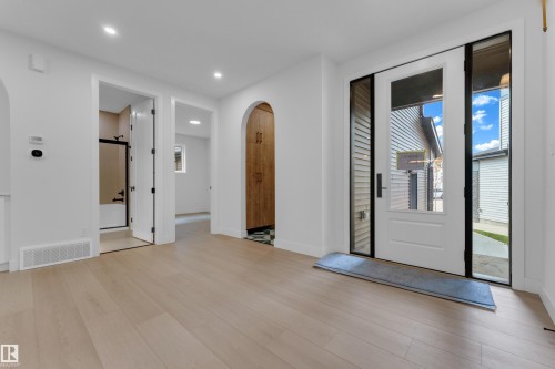 Light wood-finish flooring, recessed lighting, white interior walls, and an arched entryway - 2408 1 Avenue Sw, Edmonton, AB - Indoor Photo Showing Other Room