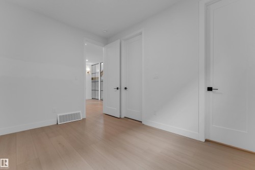 Light wood-finish flooring with white walls and trim - 2408 1 Avenue Sw, Edmonton, AB - Indoor Photo Showing Other Room