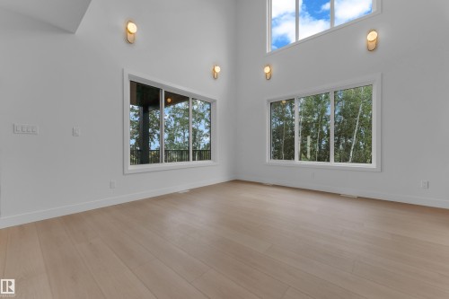 High ceilings, expansive windows, wood-finish flooring, and contemporary wall sconces - 2408 1 Avenue Sw, Edmonton, AB - Indoor Photo Showing Other Room