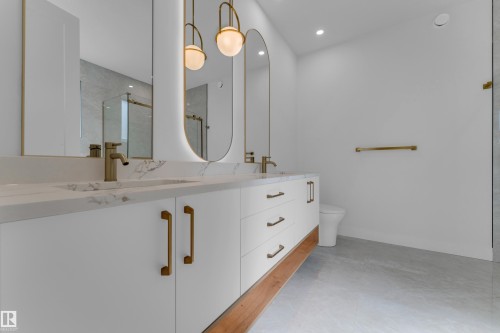 Dual vanity with white cabinetry, gold-tone hardware, and integrated sinks - 2408 1 Avenue Sw, Edmonton, AB - Indoor Photo Showing Bathroom