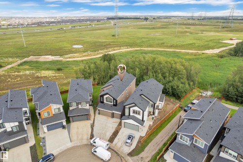 Newly constructed residences with attached garages and paved driveways, situated on a residential street with expansive green spaces in the background - 2408 1 Avenue Sw, Edmonton, AB - Outdoor With View
