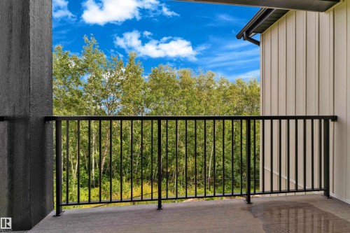 Modern composite deck with black aluminum railing featuring vertical balusters, anchored by concrete and metal posts - 2408 1 Avenue Sw, Edmonton, AB - Outdoor With Balcony
