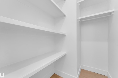 White shelving units, hanging rod, and light wood-finish flooring - 2408 1 Avenue Sw, Edmonton, AB - Indoor With Storage