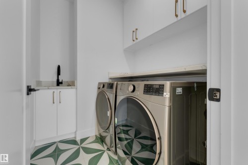 White cabinetry with gold-tone hardware, undermount sink with matte black faucet, and patterned floor tiling - 2408 1 Avenue Sw, Edmonton, AB - Indoor Photo Showing Laundry Room