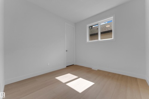 Light wood-finish flooring, white walls, and a white-framed window - 2408 1 Avenue Sw, Edmonton, AB - Indoor Photo Showing Other Room