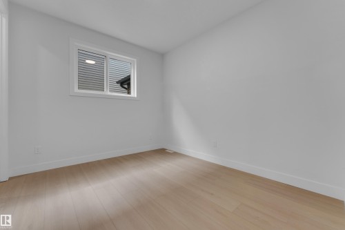 Neutral wall paint, light wood-finish flooring, and a white-framed window - 2408 1 Avenue Sw, Edmonton, AB - Indoor Photo Showing Other Room