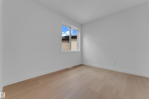 Light wood-finish flooring, white walls, and a white-framed window - 2408 1 Avenue Sw, Edmonton, AB - Indoor Photo Showing Other Room