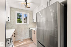 Stainless steel French door refrigerator, wood-finish flooring, white cabinetry, integrated dishwasher, and a window with exterior views - 