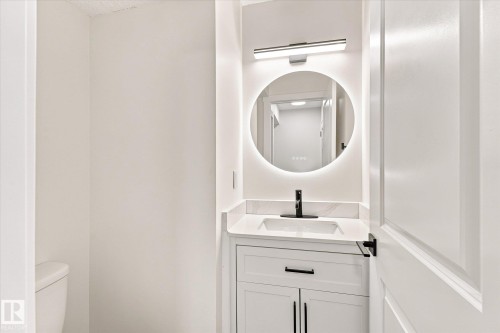 White vanity with integrated sink, sleek black faucet, and stone-finish countertop - 18307 66 Avenue Nw, Edmonton, AB - Indoor Photo Showing Bathroom