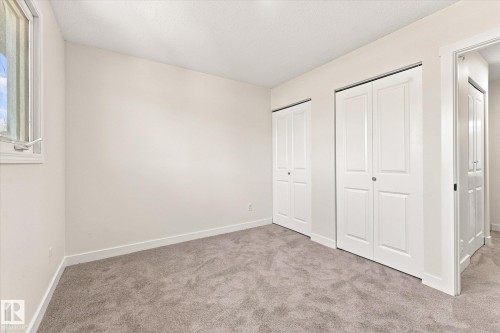 Neutral tone walls, light-colored carpeting, and white bi-fold closet doors - 18307 66 Avenue Nw, Edmonton, AB - Indoor Photo Showing Other Room