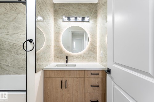 Modern vanity with wood-finish cabinetry, white countertop, and integrated sink - 18307 66 Avenue Nw, Edmonton, AB - Indoor Photo Showing Bathroom