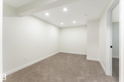 Recessed lighting, neutral wall finishes, plush carpeting, white trim, and a white interior door with black hardware - 