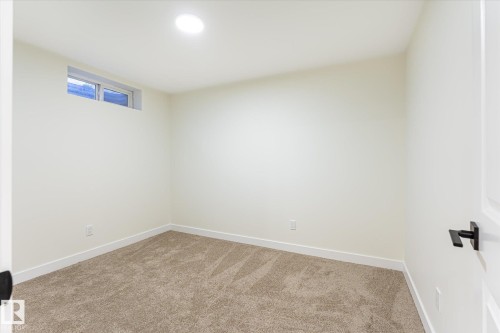 Recessed ceiling lighting, a single horizontal window, clean white walls, light brown carpet, and a white paneled door with a matte black handle - 18307 66 Avenue Nw, Edmonton, AB - Indoor Photo Showing Other Room