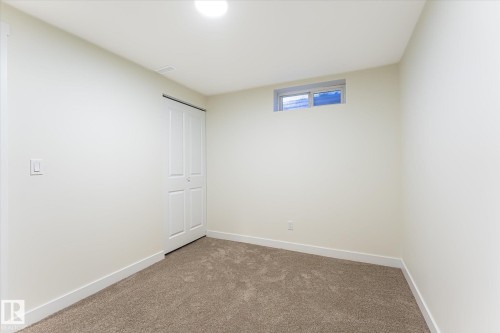 Carpeted flooring, bi-fold closet door, transom window, and flush-mount ceiling light - 18307 66 Avenue Nw, Edmonton, AB - Indoor Photo Showing Other Room