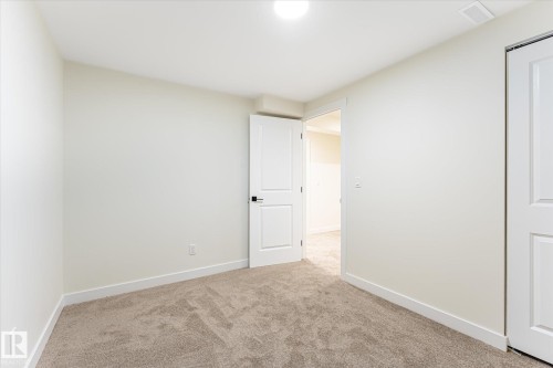 Plush carpeting, white trim, and a white interior door with black hardware - 18307 66 Avenue Nw, Edmonton, AB - Indoor Photo Showing Other Room