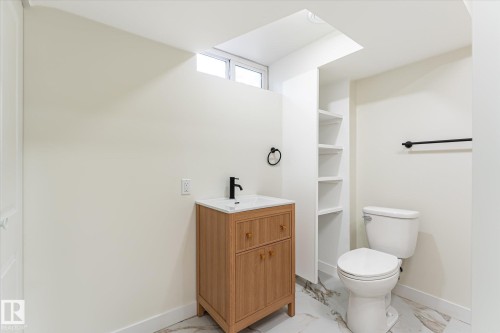 Wood-finish vanity with white countertop, matte black faucet, and white vessel sink - 18307 66 Avenue Nw, Edmonton, AB - Indoor Photo Showing Bathroom