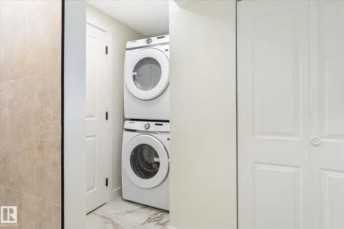 Stackable laundry appliances, panel doors, and tiled flooring - 18307 66 Avenue Nw, Edmonton, AB - Indoor Photo Showing Laundry Room