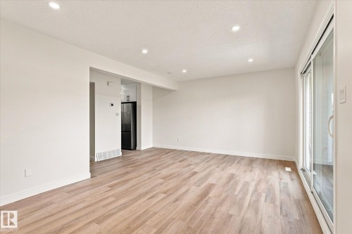 Recessed lighting, wood-finish flooring, white baseboards, and a sliding glass door - 18307 66 Avenue Nw, Edmonton, AB - Indoor Photo Showing Other Room