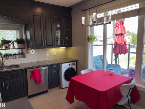 Dark wood-finish cabinetry, granite-style countertops, stainless steel appliances, and a tiled backsplash - 1452 36A Avenue Nw, Edmonton, AB - Indoor