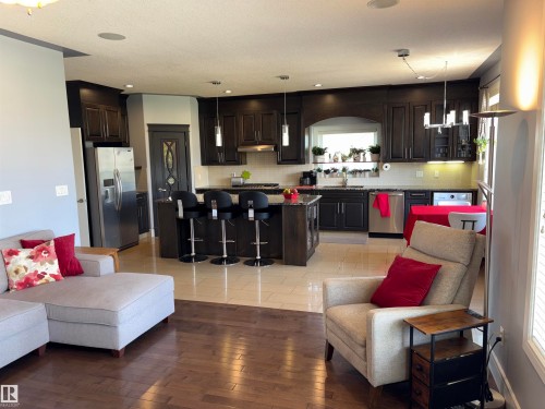 Kitchen with dark wood cabinetry, stainless steel appliances, and a central island with bar seating - 1452 36A Avenue Nw, Edmonton, AB - Indoor