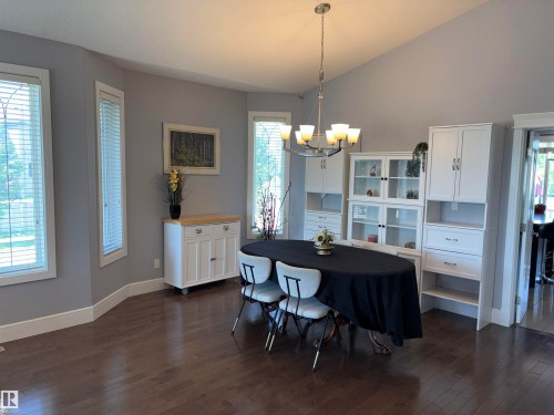 Hardwood flooring, vaulted ceiling, multiple windows, built-in cabinetry, and a contemporary chandelier - 1452 36A Avenue Nw, Edmonton, AB - Indoor Photo Showing Other Room