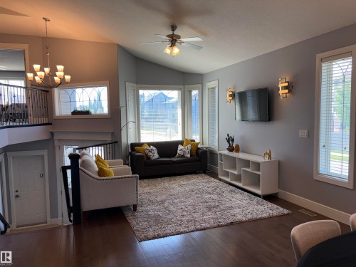 Hardwood-style flooring, vaulted ceiling, bay windows, and a decorative railing system - 1452 36A Avenue Nw, Edmonton, AB - Indoor Photo Showing Living Room
