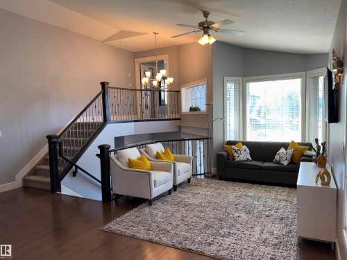 Grand staircase with wrought iron balusters, wood-finish flooring, bay windows, and a ceiling fan with integrated lighting - 1452 36A Avenue Nw, Edmonton, AB - Indoor