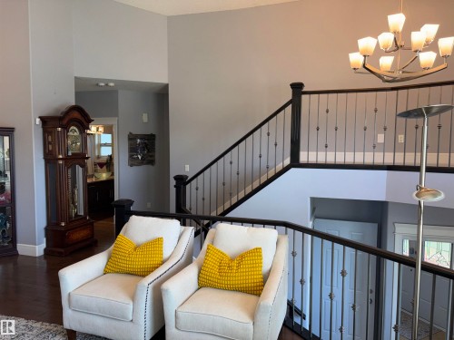 Two-story foyer featuring dark wood-finish flooring, a grand staircase with wrought iron balusters, an elegant chandelier, and vaulted ceilings - 1452 36A Avenue Nw, Edmonton, AB - Indoor
