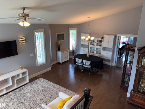 Vaulted ceiling with a ceiling fan, hardwood-finish flooring, recessed lighting, built-in display cabinetry, and a contemporary dining chandelier - 1452 36A Avenue Nw, Edmonton, AB - Indoor