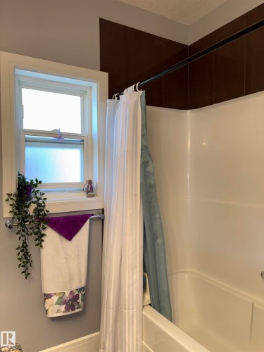 White framed window with privacy glass, chrome towel bar, and a built-in shower/tub combination - 1452 36A Avenue Nw, Edmonton, AB - Indoor Photo Showing Bathroom