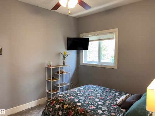 Ceiling fan with wooden blades, neutral wall paint, white window trim, and wall-to-wall carpeting - 1452 36A Avenue Nw, Edmonton, AB - Indoor Photo Showing Bedroom