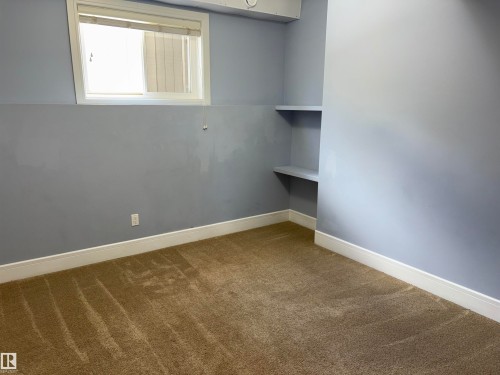 Built-in shelving, natural light from the window, and wall-to-wall carpeting - 1452 36A Avenue Nw, Edmonton, AB - Indoor Photo Showing Other Room