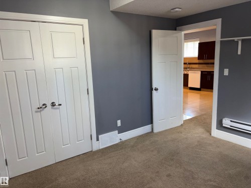 Plush carpeted flooring, white trim, and a white interior door with polished hardware - 1452 36A Avenue Nw, Edmonton, AB - Indoor Photo Showing Other Room