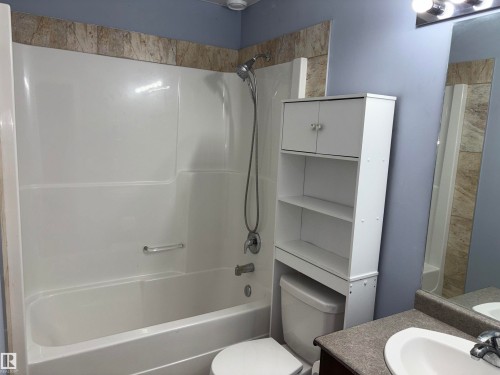 White shower-over-tub with integrated grab bar and tile surround - 1452 36A Avenue Nw, Edmonton, AB - Indoor Photo Showing Bathroom
