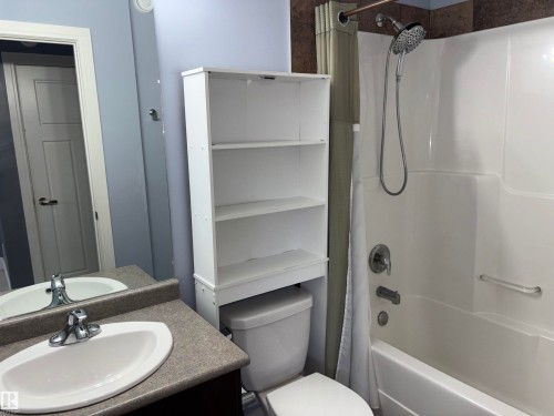 White acrylic bathtub with an integrated shower, featuring a handheld shower head - 1452 36A Avenue Nw, Edmonton, AB - Indoor Photo Showing Bathroom