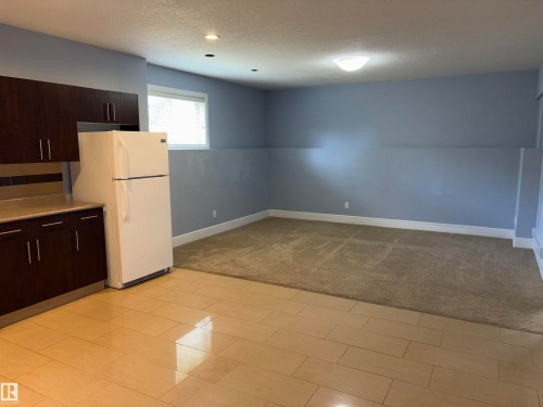 Built-in kitchen cabinetry with a light-toned countertop, recessed ceiling lighting, a single window, and a carpeted floor - 1452 36A Avenue Nw, Edmonton, AB - Indoor Photo Showing Kitchen