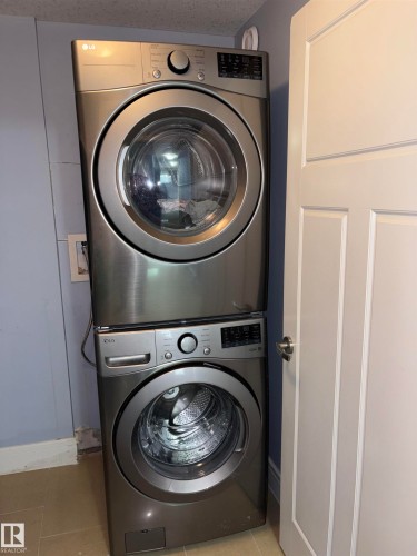 Stacked front-loading washer and dryer in a brushed metal finish - 1452 36A Avenue Nw, Edmonton, AB - Indoor Photo Showing Laundry Room