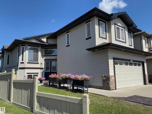 Light-toned siding exterior with dark trim accents, featuring a bay window, a dual-panel entry door, and an attached garage with a drive - 1452 36A Avenue Nw, Edmonton, AB - Outdoor
